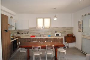 a kitchen with a wooden table and chairs at Summer Beach Rooms in Fontane Bianche