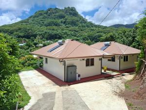 a small white house with a mountain in the background at Bungalow Miti in Uturoa
