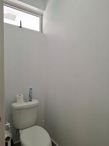 a white bathroom with a toilet and a window at Bungalow Miti in Uturoa +11 photos