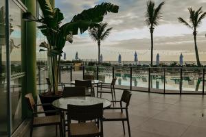 eine Terrasse mit Tischen und Stühlen und Meerblick in der Unterkunft Morada do Guaruçá in Bombinhas