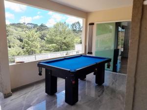 a pool table in a room with a large window at Casa da Colina Curitiba com piscina in Curitiba