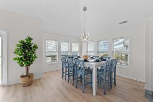 a dining room with a white table and blue chairs at 7029 - Just Breathe in Rodanthe