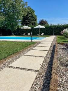 a swimming pool with two umbrellas next to at b&b VillaGresana in Villafranca di Verona
