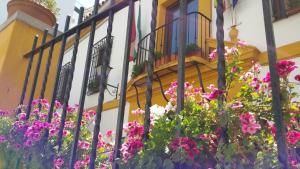 a fence with flowers in front of a building at Casa de los Naranjos in Córdoba