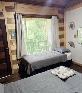 two beds in a room with a window and a table at Paroá Amazon Lodge in Manacapuru