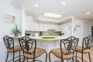 a kitchen with a counter with four chairs around it at Phoenix on the Bay 1524 in Orange Beach