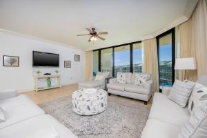 a living room with white furniture and a flat screen tv at Phoenix on the Bay 1524 in Orange Beach