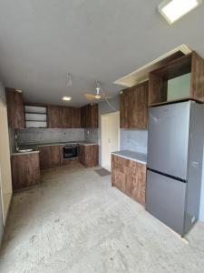 an empty kitchen with a refrigerator and wooden cabinets at Apartmani Petrović SEMČE Suva Planina in Gadžin Han +46 photos