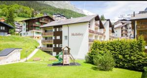 a hotel with a playground in the grass at Holiday Leukerbad Ruhe Natur Berge Free Parking 80 in Leukerbad +3 photos