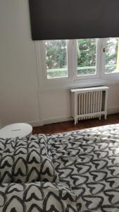 a bedroom with a black and white bed and two windows at Résidence Castors Colombes in Colombes
