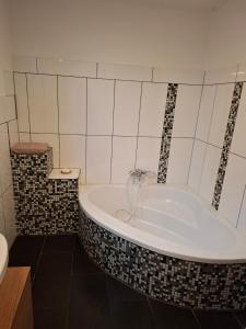 a bath tub in a bathroom with black and white tiles at Bed&Breakfast bei Sabine in Leutschach