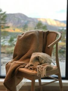 a blanket on a chair in front of a window at Spacious Mountain Cabin With View In Nissedal in Treungen +14 photos