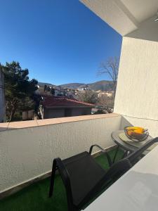 a table and a chair on a balcony with a view at Pura Vida Apartment in Mostar