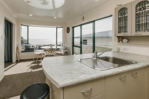 a kitchen with a sink and a living room at Oceanfront Retreat - Beach Access - 2BR Bell Block in New Plymouth +34 photos