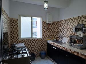 a kitchen with a stove and a sink and a window at APPARTEMENT AL HOCEIMA prés de PLAGE CALABONITA in Al Hoceïma