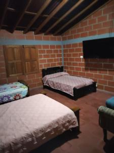 a room with two beds and a brick wall at Casa Hotel los Patios in Jericó +10 photos