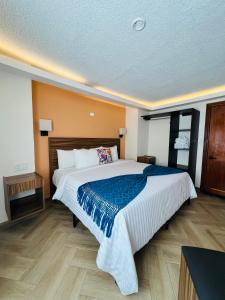 a bedroom with a large bed with a blue blanket at Suites del Jardín Principal in Guanajuato