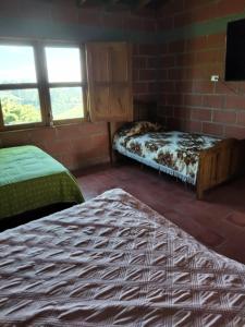 a room with two beds and a tv in it at Casa Hotel los Patios in Jericó