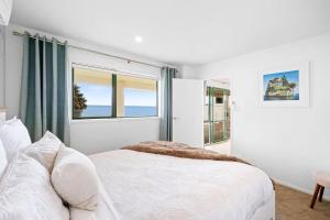a white bedroom with a bed and a window at Beachfront Studio - Ocean Views - Bell Block in New Plymouth