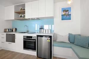 a kitchen with a stainless steel refrigerator and a couch at Beachfront Studio - Ocean Views - Bell Block in New Plymouth