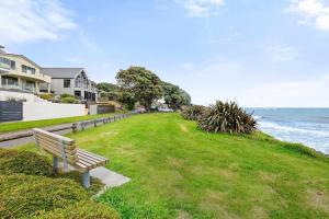 a bench sitting on the grass near the ocean at Beachfront Studio - Ocean Views - Bell Block in New Plymouth