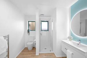 a white bathroom with a shower and a toilet at Beachfront Studio - Ocean Views - Bell Block in New Plymouth +14 photos