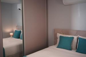 a mirror in a bedroom with two beds and blue pillows at Pauloldtown - Local experience w rooftop n jacuzzi in Paul do Mar