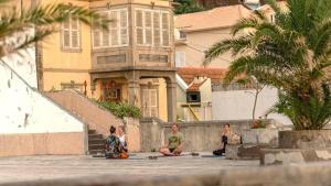 a group of people sitting on a wall in front of a building at Pauloldtown - Local experience w rooftop n jacuzzi in Paul do Mar