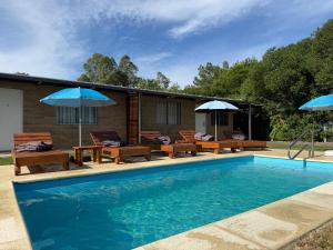 a swimming pool with patio furniture and umbrellas at Complejo San San in San Luis
