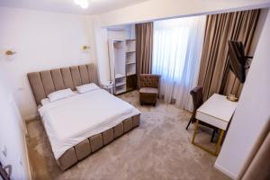 a bedroom with a bed and a chair and a desk at Villa Jolie in Craiova