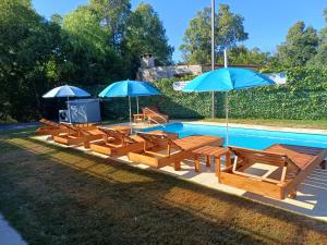 a group of benches and umbrellas next to a pool at Complejo San San in San Luis
