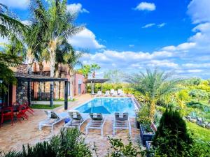 a backyard with a swimming pool and chairs and palm trees at Villa Malika Private Luxury Villa Marrakech in Tameslouht