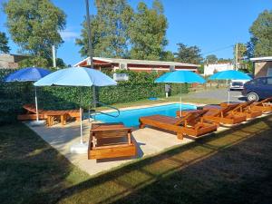 a swimming pool with benches and umbrellas at Complejo San San Apto 201 in San Luis +9 photos