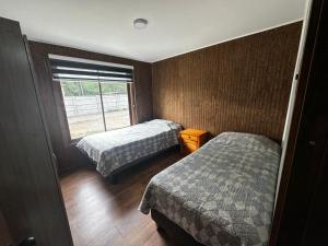 two beds in a small room with a window at Cabañas y hospedaje kalú in Nueva Imperial