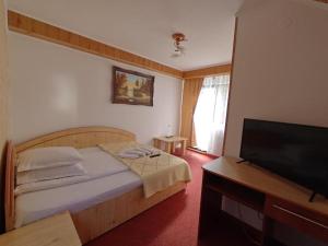 a bedroom with a bed and a flat screen tv at Pensiunea Dana Olteanu in Moieciu de Sus