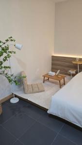 a bedroom with a bed and a bench and a table at Sleep Owl Surat Thani in Surat Thani +27 photos