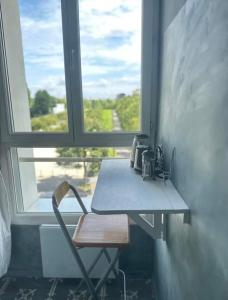 a chair sitting next to a table in front of a window at Petit nid calme à 2 pas de Paris in Ivry-sur-Seine
