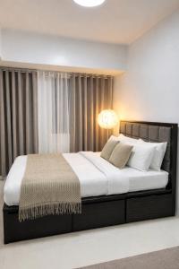a bedroom with a large bed with a lamp on it at La Montañosa at Brenthill Baguio Condo near City Center in Baguio