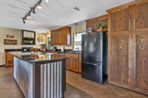 a kitchen with a black refrigerator and wooden cabinets at 2 Creeks in Wimberley