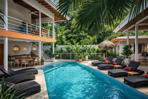 an outdoor pool with lounge chairs and a villa at Sanctuary Puerto Viejo in Cocles