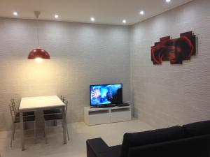 a living room with a table and a tv on a wall at Villa Bebe' in Vico Equense