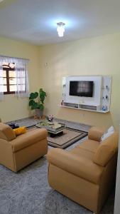 a living room with two couches and a flat screen tv at Casa Linear Térrea com Piscina no Atlântico in Rio das Ostras