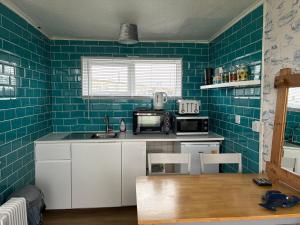 a kitchen with blue tiles on the walls at Chalet 65 in Chapel Saint Leonards