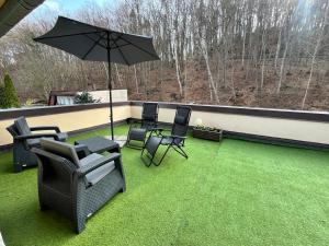 a patio with chairs and an umbrella on the grass at Spokojny Potok Sopot - AFRA GROUP in Sopot