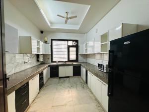 a large kitchen with white cabinets and a black refrigerator at Remix stays in Gurgaon