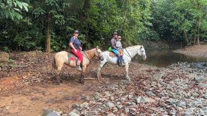 a couple of people riding on horses near a river at Sabalo Lodge Tours and Cabins in Sierpe +94 photos
