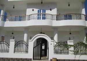 a white building with a balcony and a black door at Nile Paradise Apartments in Luxor