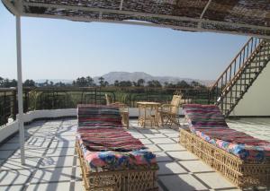 a patio with two chairs and a table on a roof at Nile Paradise Apartments in Luxor