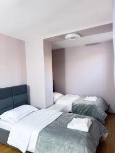 three beds in a room with white walls at Trea Apartment in Tirana