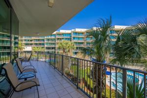 a balcony with chairs and palm trees and a resort at Phoenix on the Bay 1213 in Orange Beach